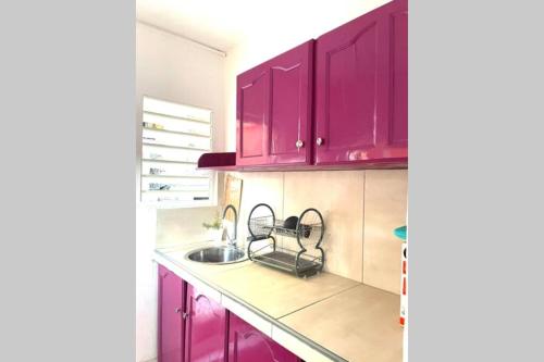 a kitchen with purple cabinets and a sink at Maénorah 30s de la belle plage Carbetienne in Le Carbet