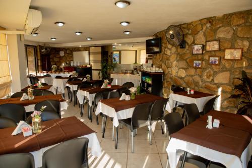 a restaurant with tables and chairs and a stone wall at Villa La Font Apart Hotel & Spa in Villa Carlos Paz