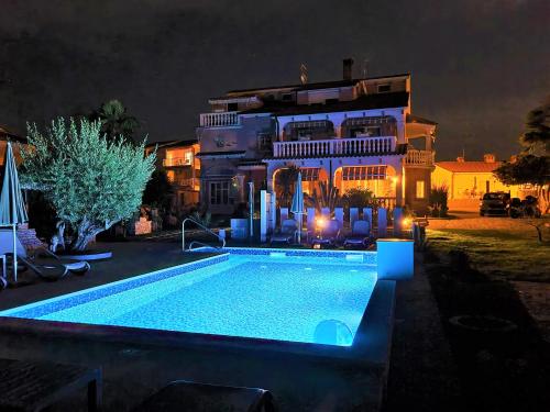 una piscina frente a una casa por la noche en Apartment Villa Engel with Pool, en Poreč