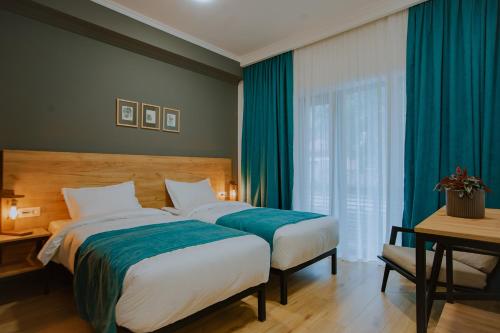 two beds in a hotel room with blue curtains at Northgate Hotel Kazbegi in Stepantsminda