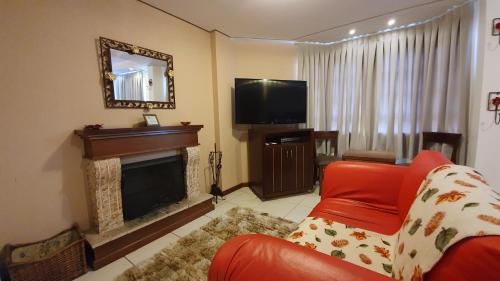 uma sala de estar com lareira e um sofá vermelho em Pousada Cheverny - Fácil acesso ao centrinho e Baden Bar em Campos do Jordão