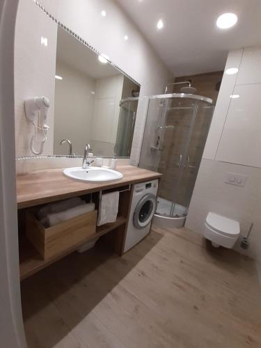 a bathroom with a sink and a washing machine at Apartament Baltic Meridian Pobierowo in Pobierowo