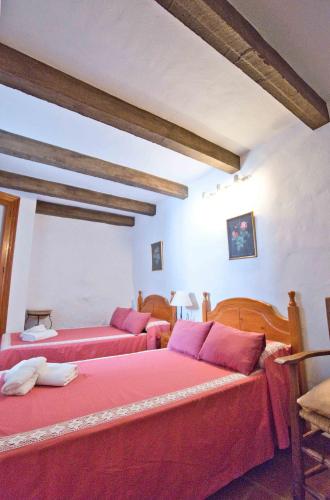 a bedroom with two beds with red sheets at La Madroñala in El Gastor