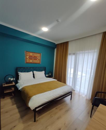a bedroom with a large bed with a blue wall at Northgate Hotel Kazbegi in Stepantsminda