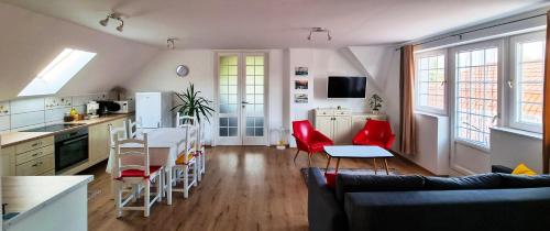 a kitchen and living room with a table and red chairs at White Apartment in Keszthely