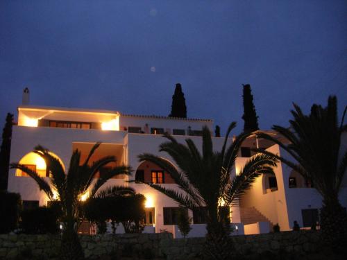 a white building with palm trees in front of it at SORINA Beloved Rooms in Spetses