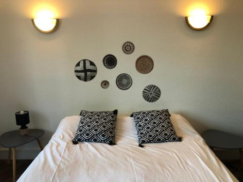 Chez FIRMIN "Les Ombrages" في Mesnac: غرفة نوم مع سرير مع وسادتين وصحون على الحائط