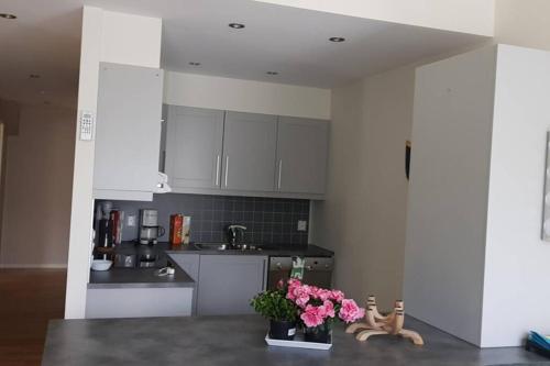 a kitchen with white cabinets and pink flowers on a counter at Flott leilighet på Tysnes in Tysnes