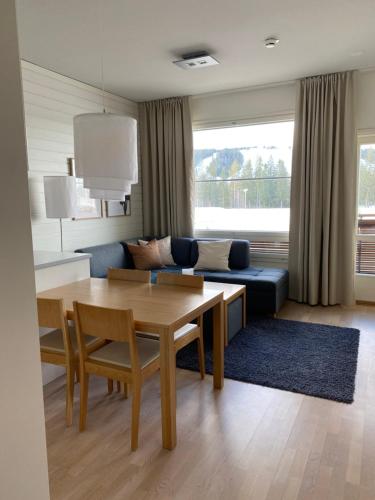 a living room with a table and a blue couch at Tahko Chalets B402 in Tahkovuori