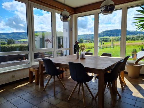 a dining room with a table and chairs and windows at MUT.HAUS in Bischofsheim an der Rhön