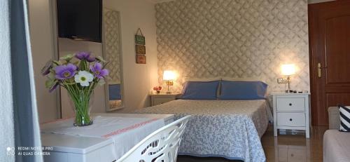 a bedroom with a bed with a vase of flowers at Suite Mirando al Guadiana in Ayamonte