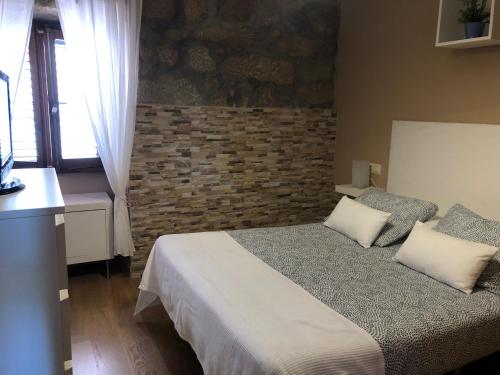um quarto com uma cama e uma parede de tijolos em Casita rural acogedora em Combarro