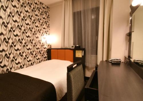 a bedroom with a bed and a desk with a telephone at APA Hotel Kanazawa Katamachi in Kanazawa