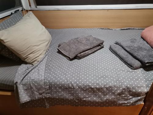 Una cama con sábanas de lunares y toallas. en Green Garden Caravan en Zakynthos