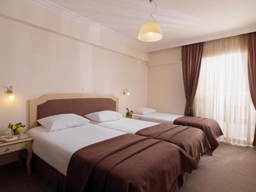 a hotel room with two beds and a window at Airotel Parthenon in Athens