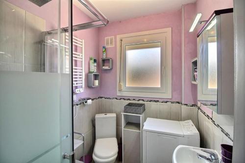 une salle de bains rose avec toilettes et lavabo. dans l'établissement Appartement à 50 mètres de la mer - Les embruns, à Berck-sur-Mer