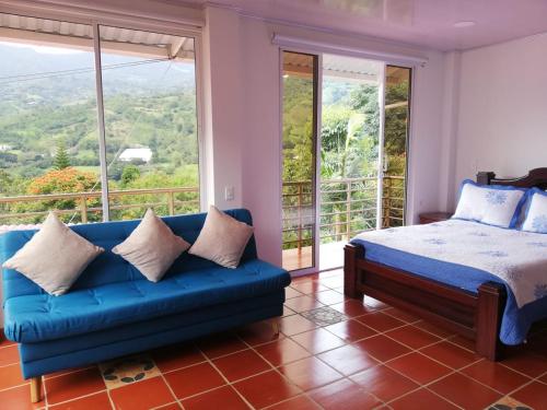 1 dormitorio con sofá azul y balcón en Cabaña Campestre Santa Helena, en Choachí