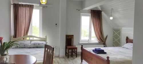 a bedroom with a bed and a table and two windows at Conacul Mierii in Străşeni