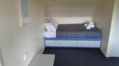 a small room with a bed with white pillows at Alpine Chalets in National Park
