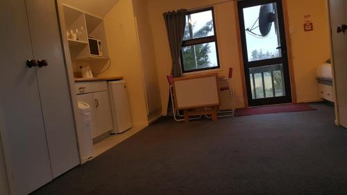a room with a kitchen with a table and two windows at Alpine Chalets in National Park