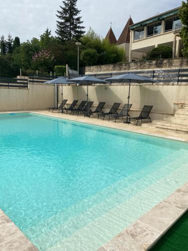 a large swimming pool with chairs and umbrellas at Appart’hôtel les perles du lac in Tombeboeuf