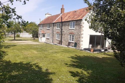 an old stone house with a grass yard in front of it at Characterful Cottage adjacent to an Orchard in Brockley