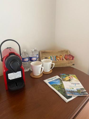 a table with a coffee maker and a book and cups at LE BAS CHITRAY in Ménil