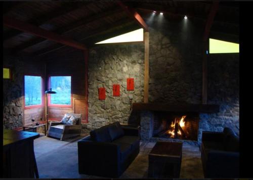 a living room with a fireplace and a stone wall at Las Pitras Lodge in Epuyén