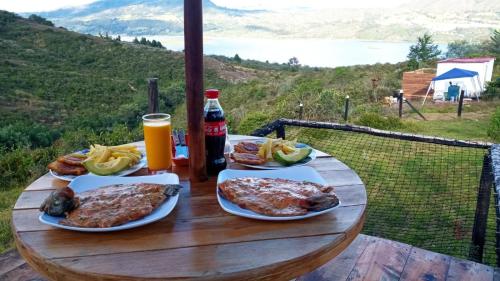 una mesa de madera con platos de comida y una botella de refresco en Glamping Bella Vista en Guatavita