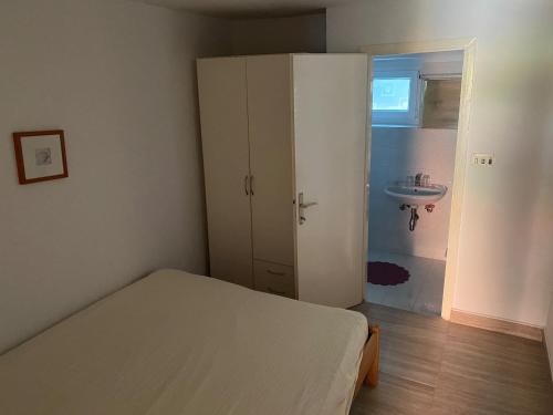 a small bedroom with a bed and a sink at Casita Liliana By the Sea in Mali Lošinj