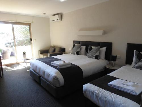a hotel room with two beds and a window at Wine Village Motor Inn in Rutherglen