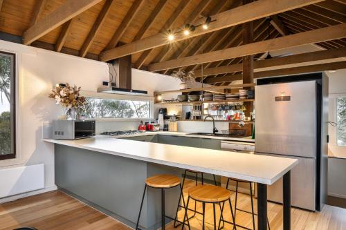 a kitchen with a large white counter and stools at Belltrees in Dinner Plain