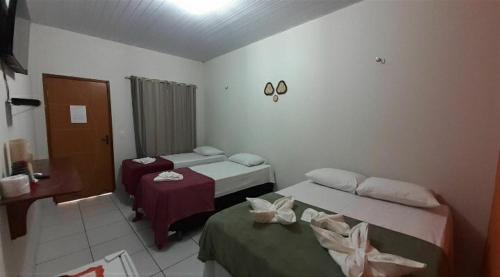 a hotel room with two beds and a desk and a room at Pousada Chácara do Coqueiro in Barreirinhas
