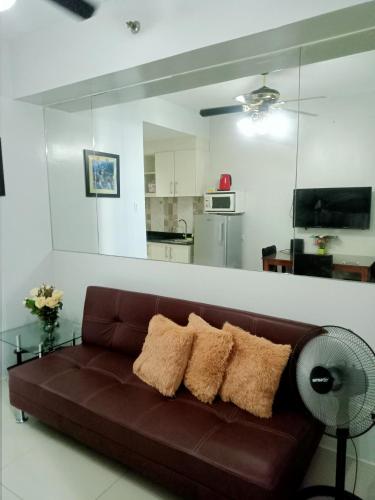 a brown couch in a living room with a kitchen at SEA RESIDENCES F in Manila