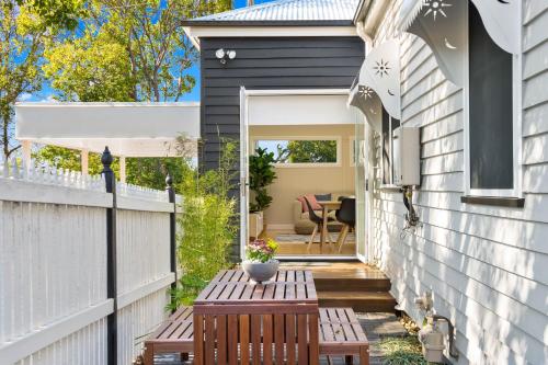a small patio with a wooden table and a fence at Bluestone Cottages - The Shop in Toowoomba