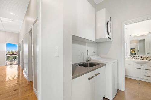 una cucina bianca con lavandino e specchio di Bluestone Cottages - The Shop a Toowoomba