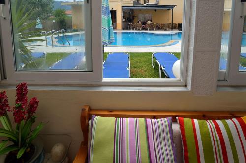 a view of a swimming pool through two windows at Eleni Apartments in Roda