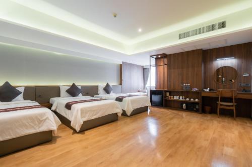 a hotel room with three beds and a desk at True Siam Phayathai Hotel in Bangkok