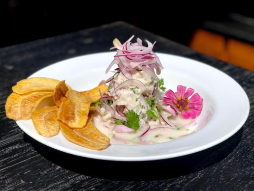 a white plate with a salad and chips on a table at Pousada do Vale in Fernando de Noronha