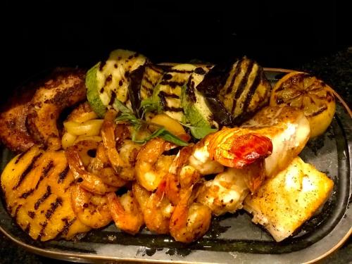 a plate of food with shrimp and vegetables on a table at Pousada do Vale in Fernando de Noronha