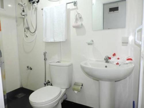a white bathroom with a toilet and a sink at Capital Regency in Kandy