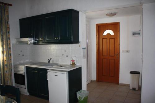 a kitchen with green cabinets and a sink and a door at Votsalo Apartments in Patitiri