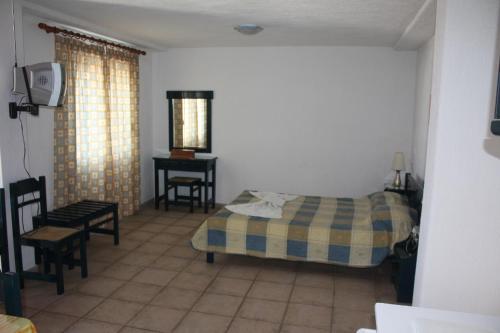 a bedroom with a bed and a table and a chair at Votsalo Apartments in Patitiri