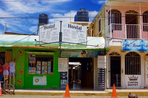 a green building with signs on it on a street at Hostal Los Chamos in San Juan del Sur