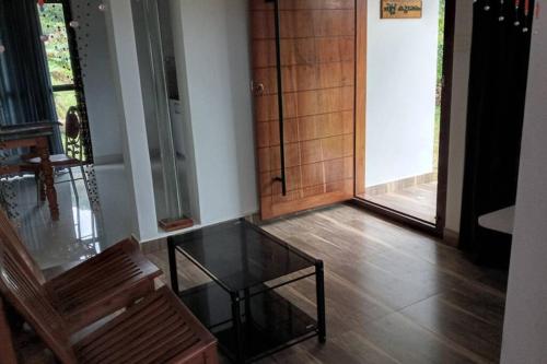 a room with a glass table and a wooden door at Farmstay in ചില്ലുകൂടാരം at Les Domki et al. in Vagamon