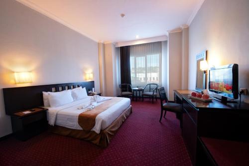 クパンにあるKristal Hotel Kupangのベッド、デスク、テレビが備わるホテルルームです。