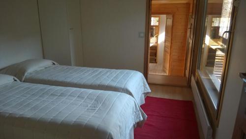 two beds in a room with a door to a porch at Kuoreksenniemi Villas & Lakehouse in Puumala