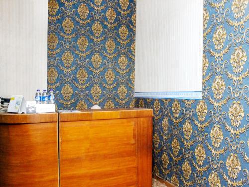 a kitchen with blue and gold wallpaper and a wooden cabinet at SPOT ON 2353 Wisma Hulubalang in Palembang