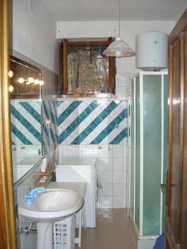 a small bathroom with a sink and a shower at Sa Domu Sarda casa vacanza in Piscinas