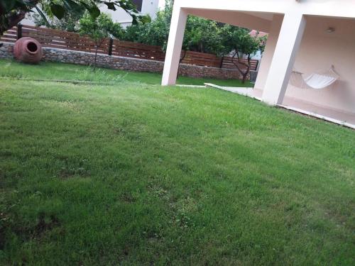 a yard with green grass and a fence and a hammock at THALASSA ALMYROS APARTMENTS in Almirón